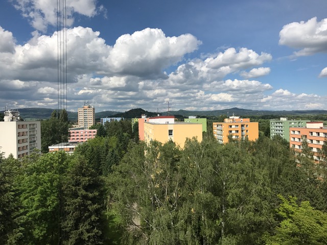 Pohled severovýchodním směrem na s bytovým domem sousedící panelové domy, které jsou součástí Valdického předměstí, na obzoru Krkonošské podhůří.
